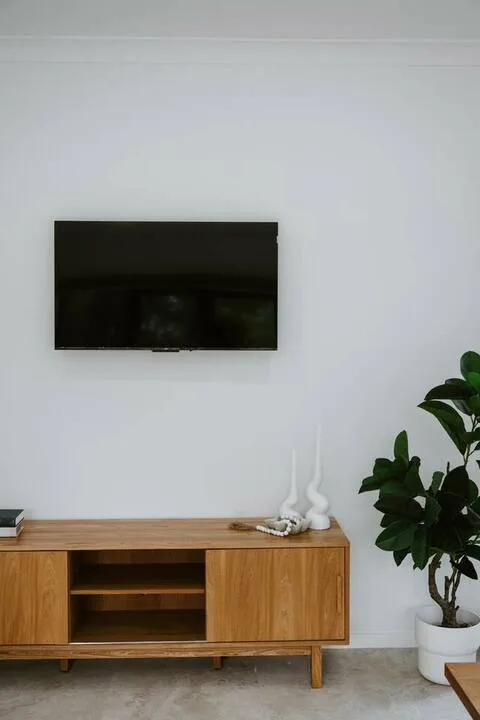 A living room with a wall-mounted television above a wooden media console.