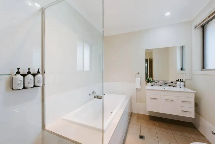 A bright bathroom with a glass-enclosed shower and a vanity with a mirror.