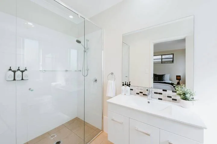 A bright bathroom with a glass shower and a wide vanity.
