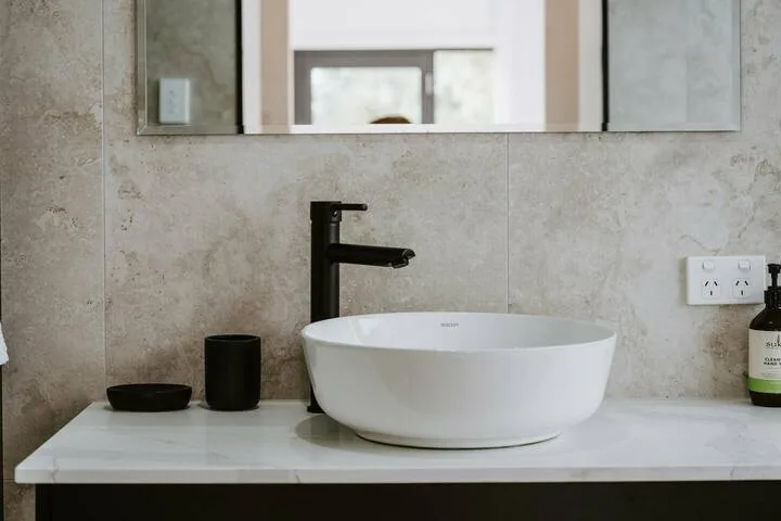A bathroom vanity with a white vessel sink and black faucet.
