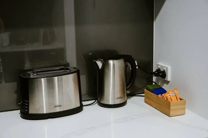A kitchen counter with a stainless steel toaster, electric kettle, and tea supplies.