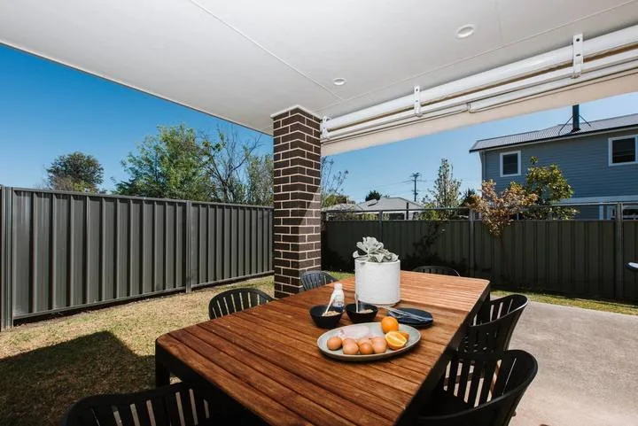 A covered patio with a wooden dining table and chairs.
