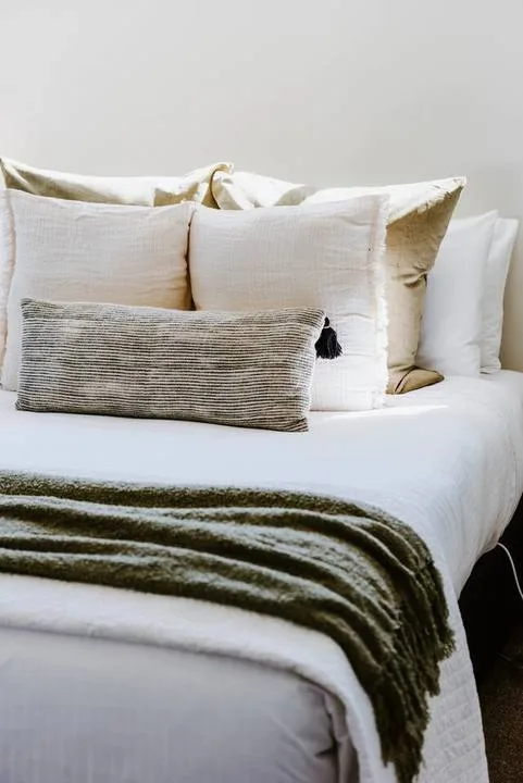 A neatly made bed with layered pillows and a dark textured throw.