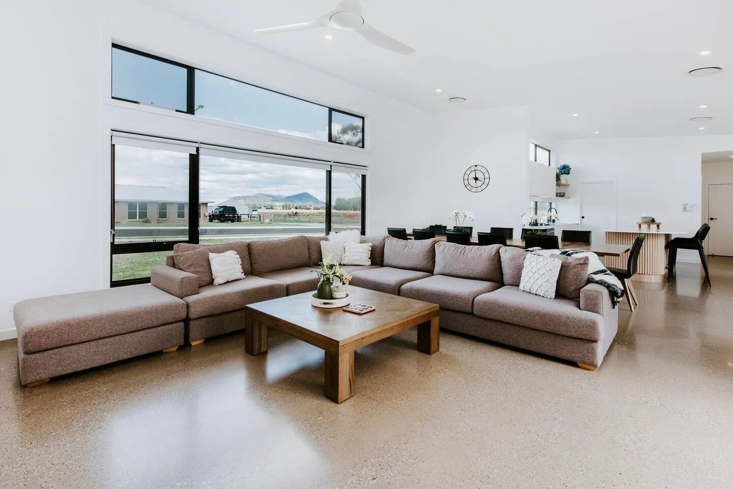 A bright living room with sectional seating, a coffee table, and large windows.