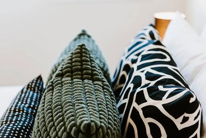 A bed with patterned pillows and white bedding.