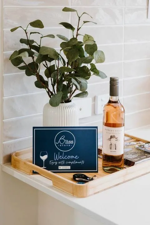 A welcome tray with a bottle and a leafy plant sits on a counter.
