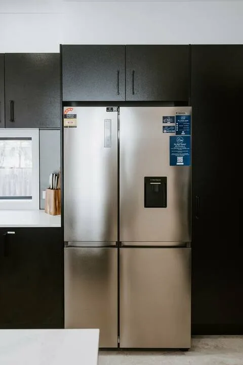 A modern kitchen with a stainless steel refrigerator and dark cabinets.