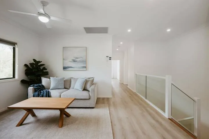 A bright living area with seating, a coffee table, and a hallway.
