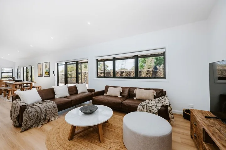 A bright living room with brown seating arranged around a low coffee table.