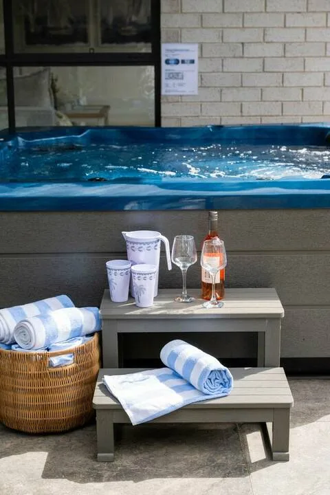 A small poolside soaking tub with towels and drinks arranged on low tables.