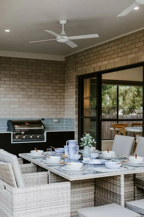 A dining area with a set table and wicker seating beside a glass doorway.