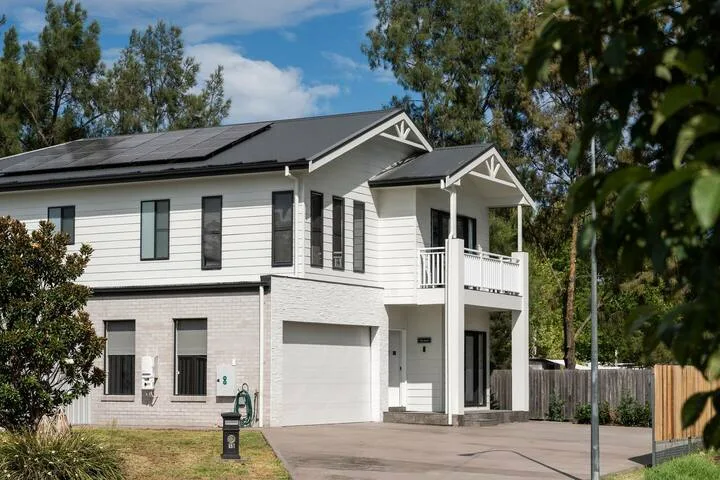 A modern two-story house with white siding, a garage, and a driveway.