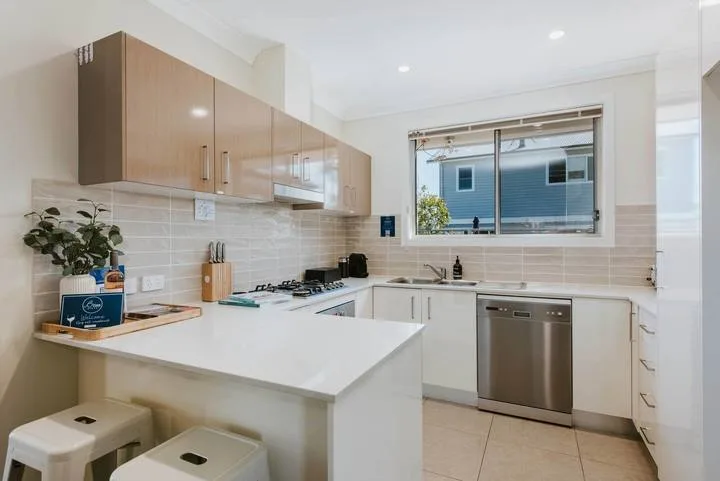A bright kitchen with a white island, light cabinetry, and a window above the sink.