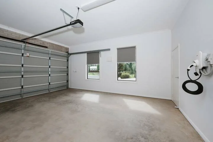 A garage with a wide sectional door and two windows.