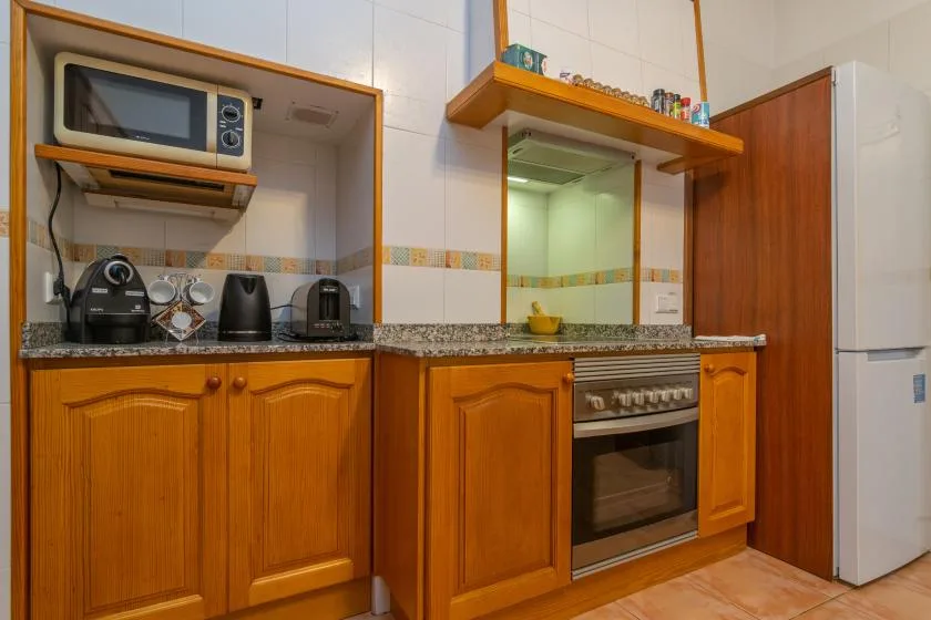 Una cocina con gabinetes de madera, una encimera y un horno integrado.