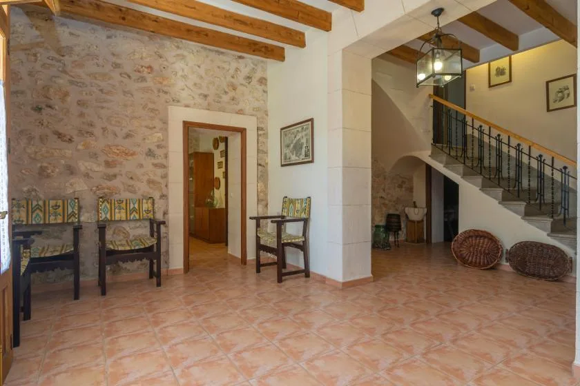 Un amplio recibidor con paredes de piedra, vigas de madera vistas y una escalera.