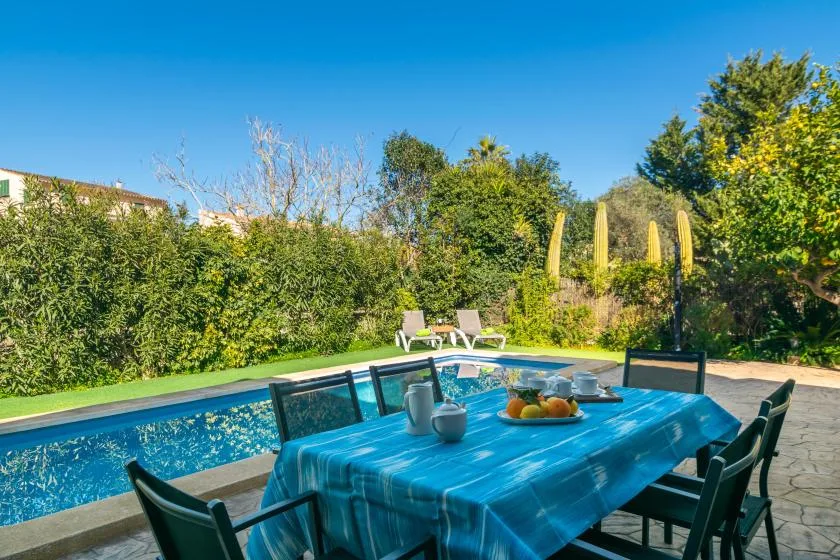 Una zona de comedor al aire libre junto a una piscina, con una mesa preparada para comer.