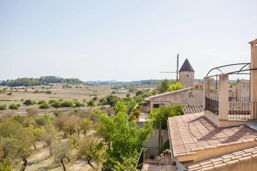 Una terraza da a un amplio paisaje rural, con una pequeña torre cerca.