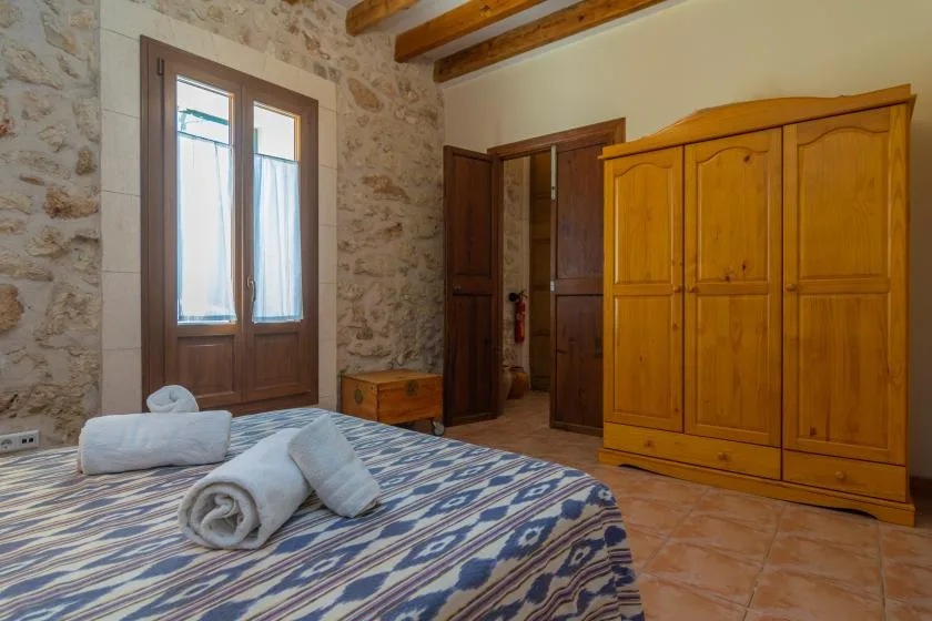 Un dormitorio con ropa de cama estampada, un armario de madera y una ventana.