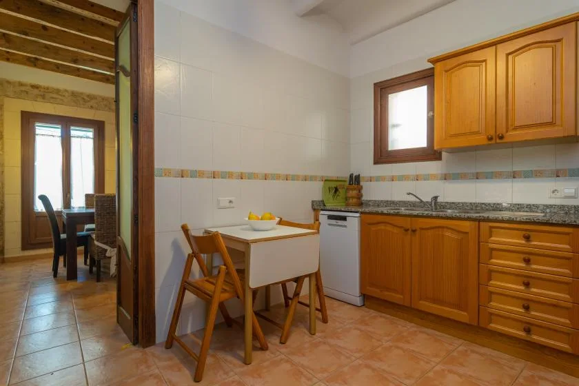 Una cocina con gabinetes de madera, un fregadero y una pequeña mesa de comedor.