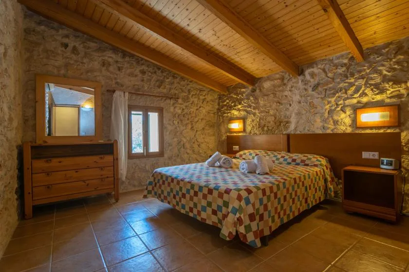 Un dormitorio con una cama doble bajo un techo de madera y paredes de piedra vista.