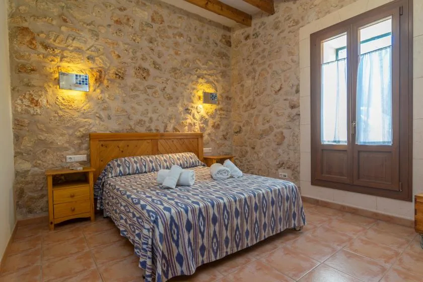 Un dormitorio con cama doble, ropa de cama estampada y paredes de piedra.