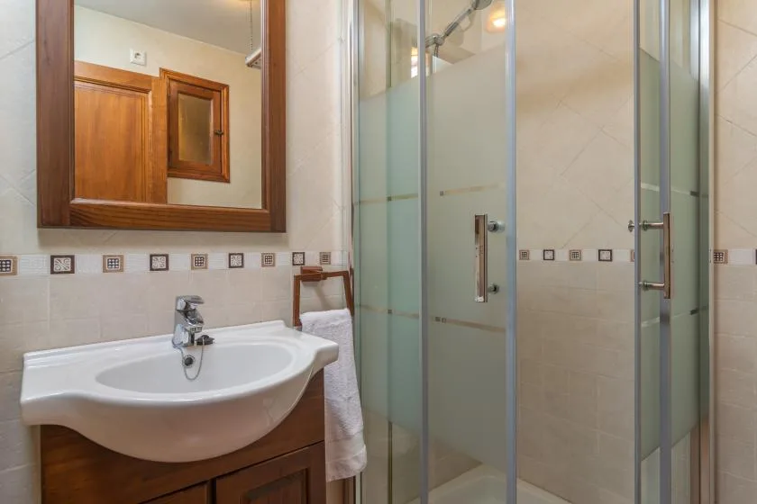 Un baño con lavabo, espejo de pared y ducha de vidrio.