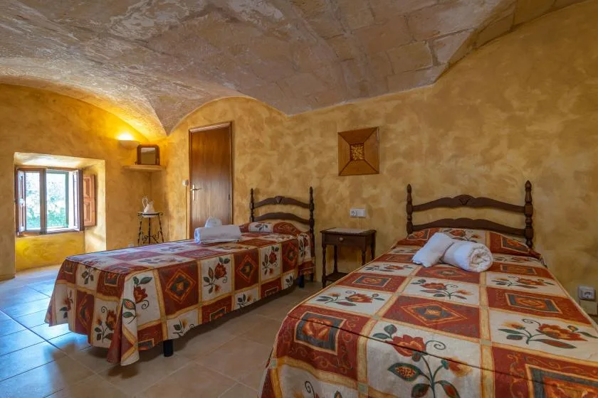 Un dormitorio con dos camas cubiertas con colchas coloridas y estampadas.