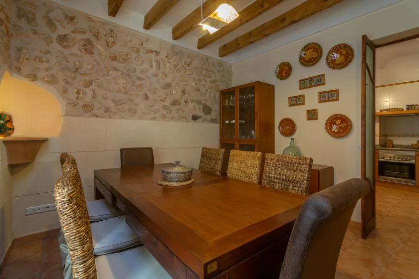 Un comedor con una mesa de madera y asientos de tejido bajo vigas expuestas.