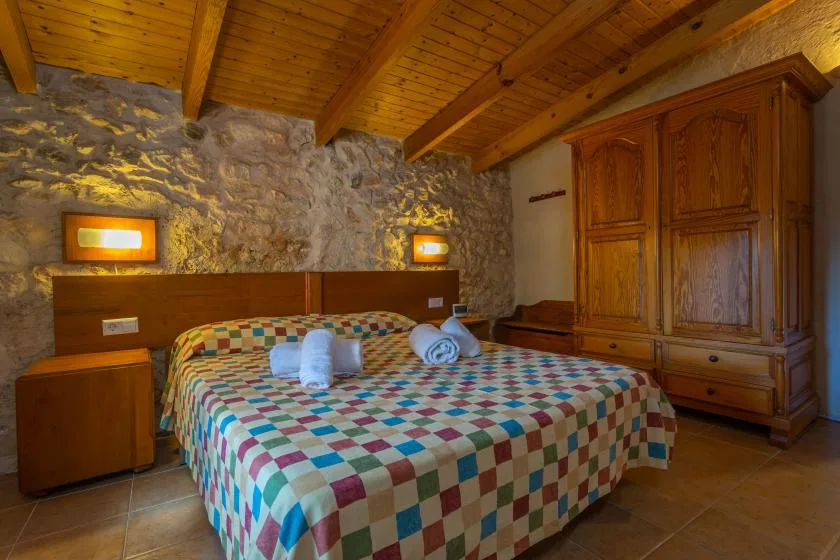 Un dormitorio con una colcha de retazos colorida y un armario de madera.