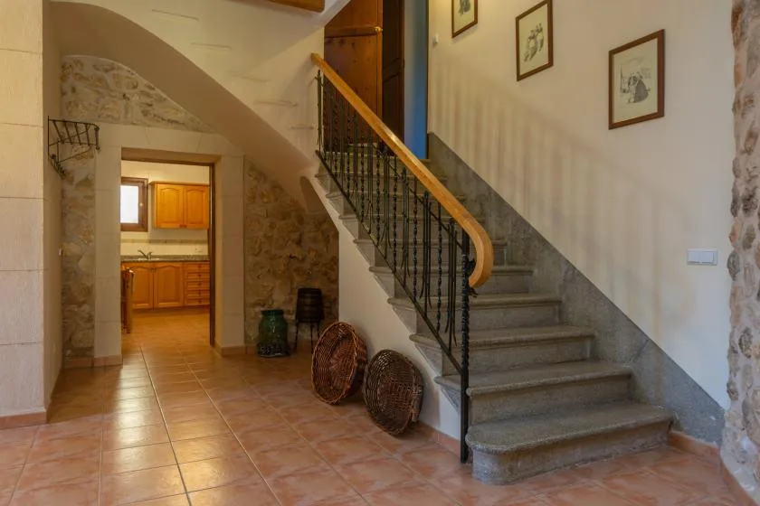 Un recibidor con suelo de baldosas, una escalera de piedra y una puerta hacia la cocina.