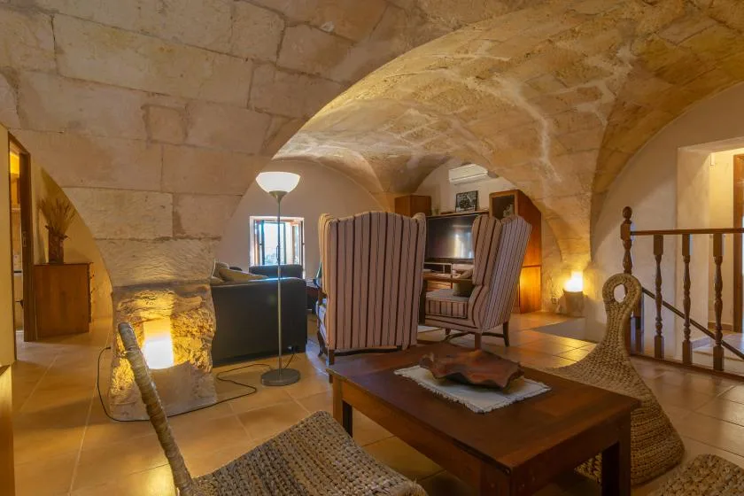 Una acogedora sala de estar de piedra con techos abovedados y una zona de asientos.