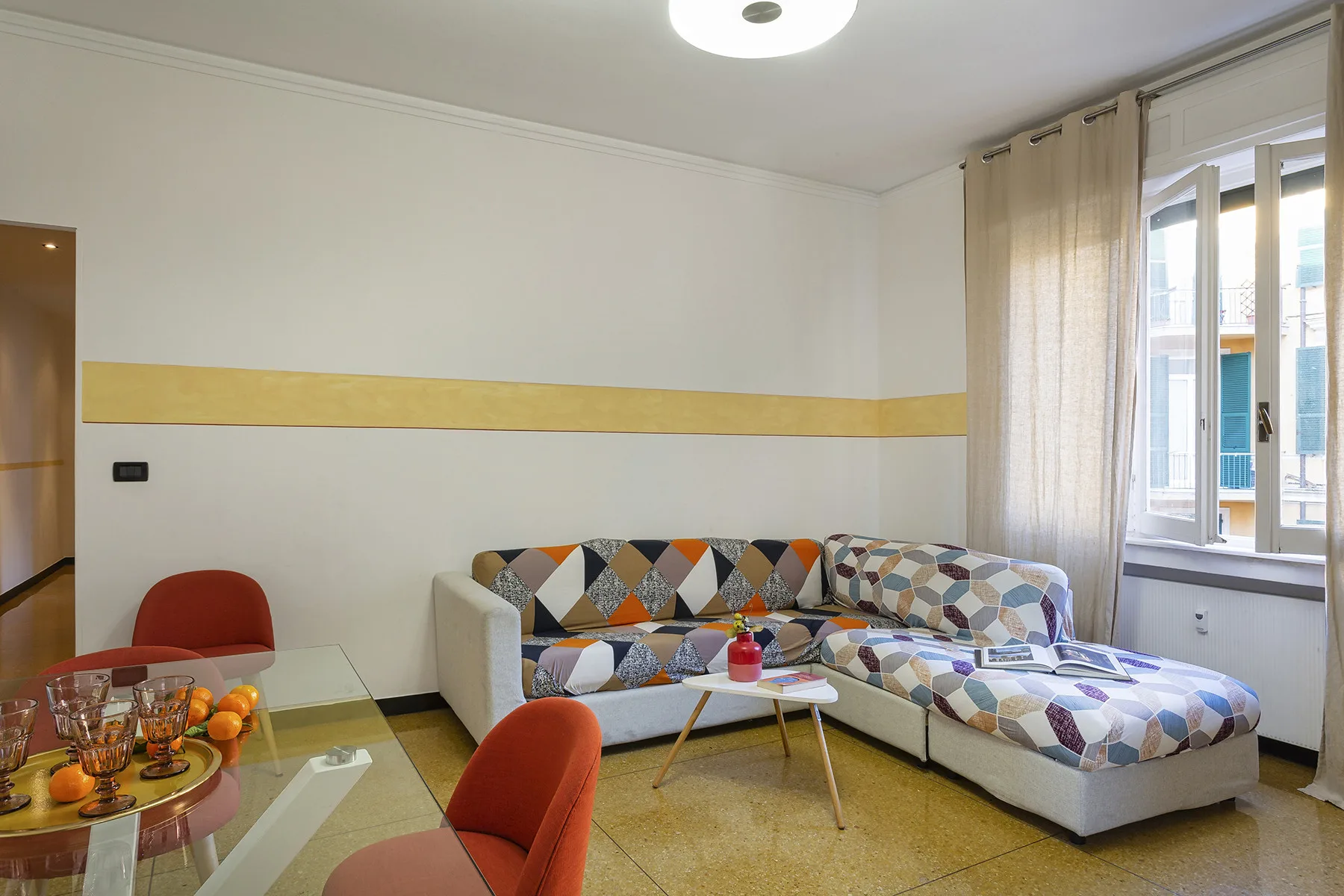 A bright living room with patterned seating beside a large window.