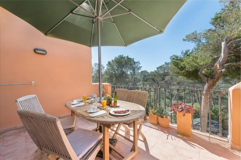 Un comedor al aire libre con una mesa y sillas bajo una sombrilla grande.