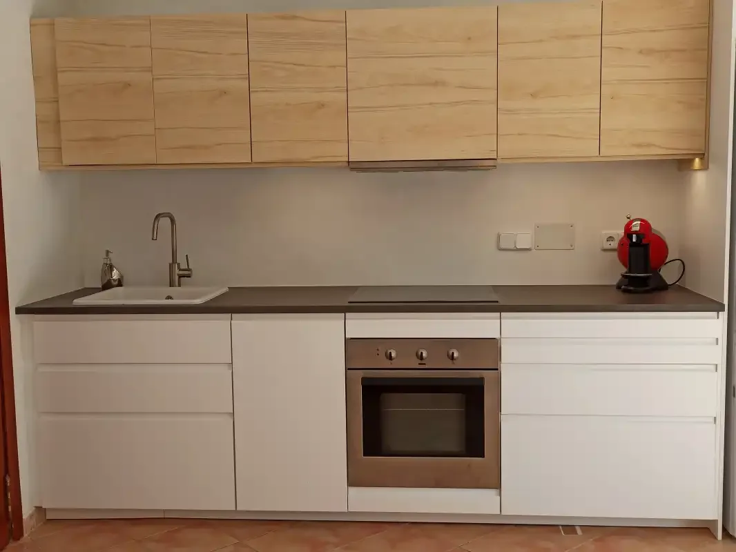 Una cocina moderna con fregadero, horno y cafetera roja.