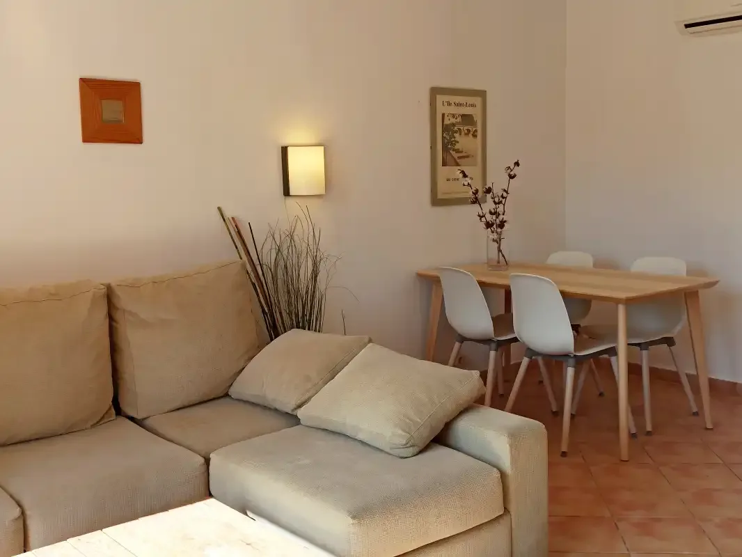 Una sala de estar y comedor con un sofá beige y una mesa de madera.