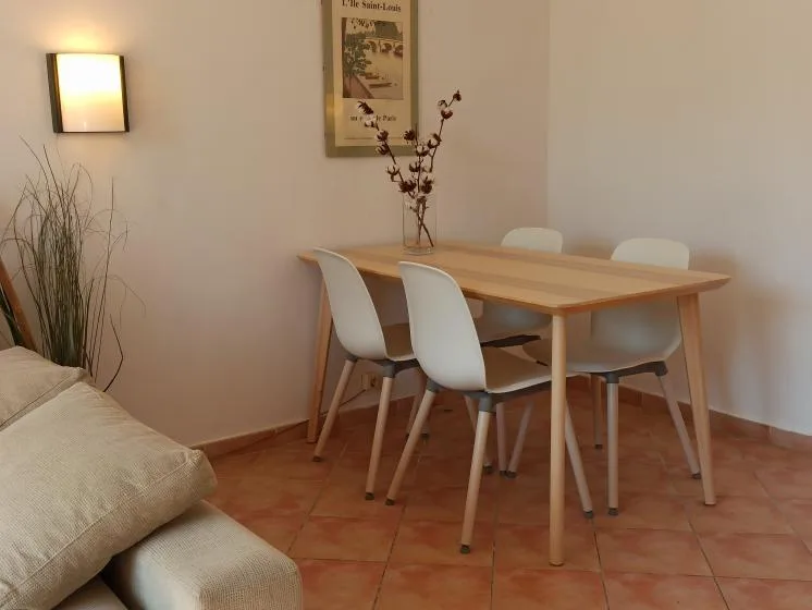 Comedor con una mesa de madera y asientos blancos.