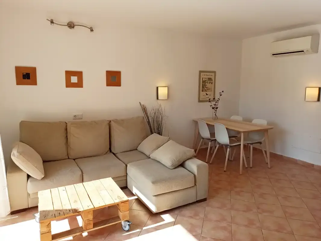 Una sala de estar con un sofá beige y una mesa de comedor.