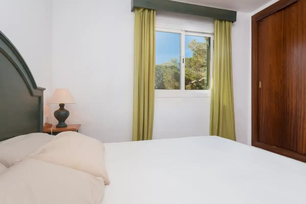 Un dormitorio con una cama junto a una ventana enmarcada por cortinas amarillas.