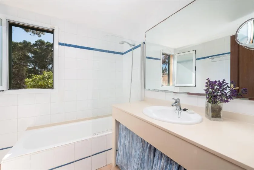 Un baño luminoso con bañera, un espejo grande y un lavabo.
