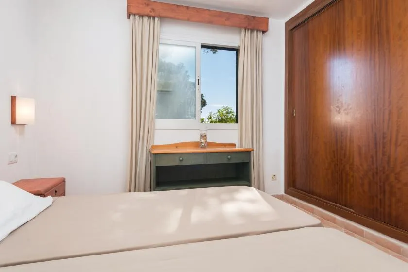 Un dormitorio con una cama, una ventana y un armario de madera.