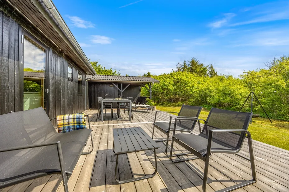 Una terraza exterior con asientos y una mesa junto a una casa.