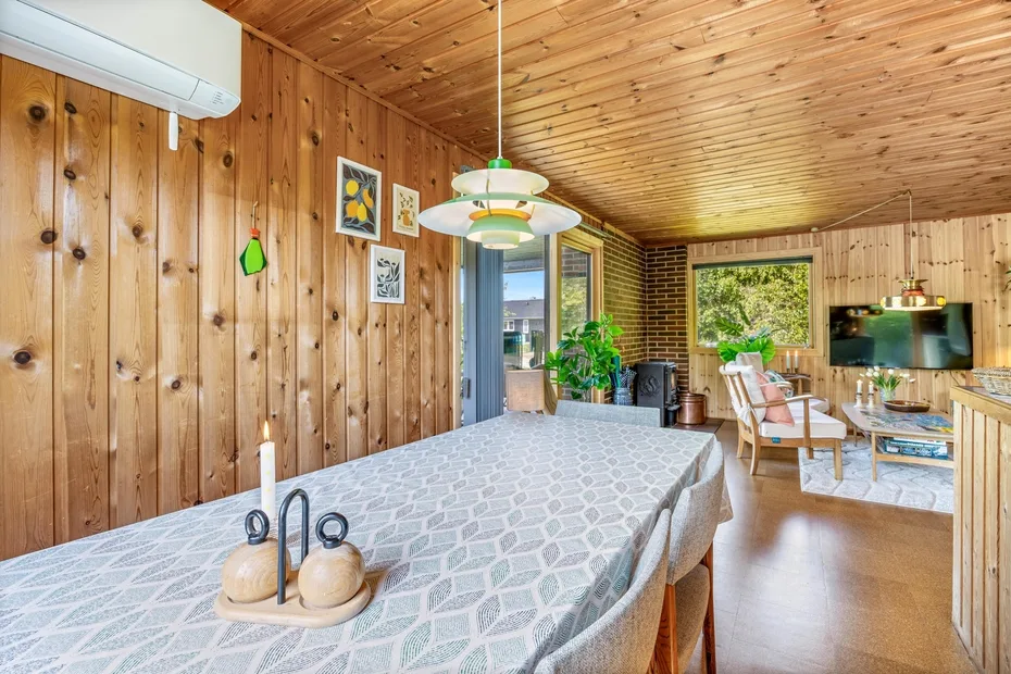 Una sala-comedor revestida de madera, con una mesa grande y asientos.
