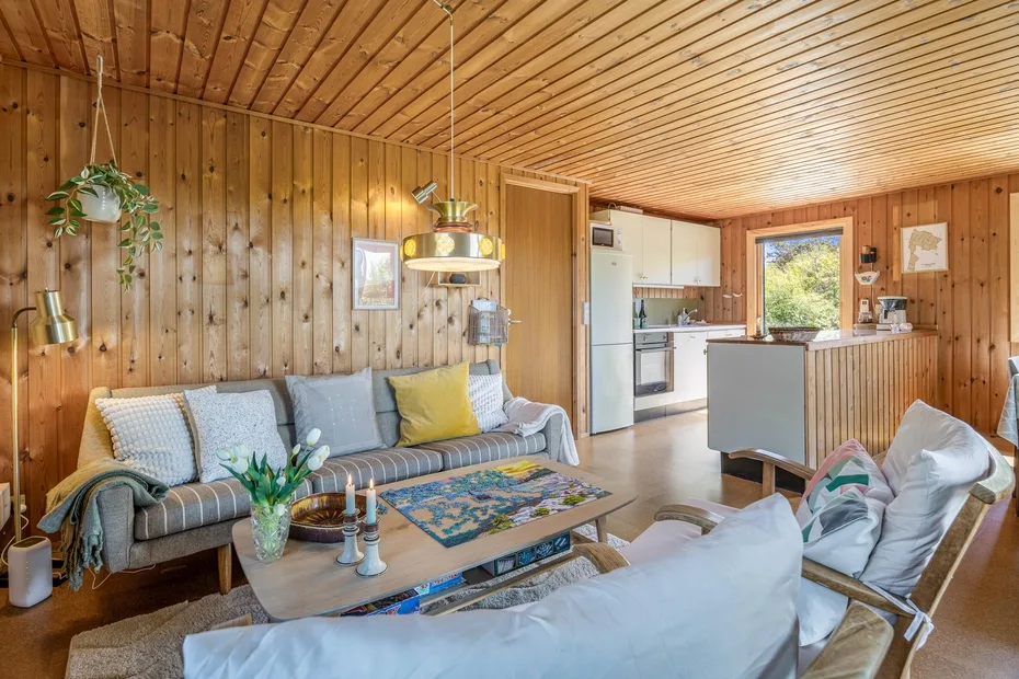 Una sala revestida de madera con asientos y una cocina abierta.