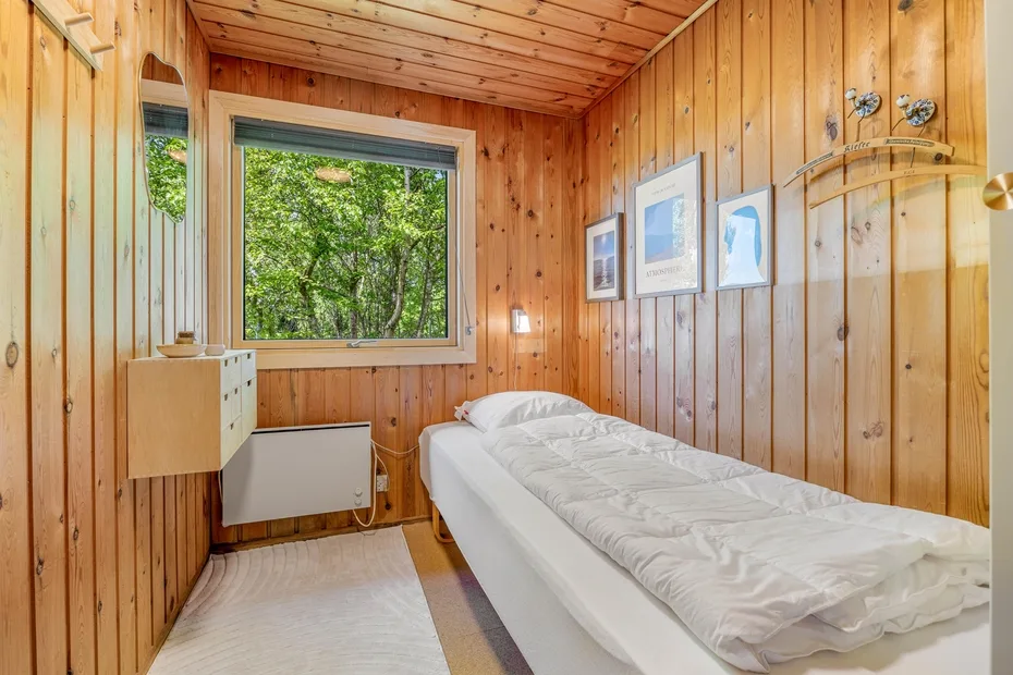 Un dormitorio revestido de madera con una cama debajo de cuadros enmarcados.