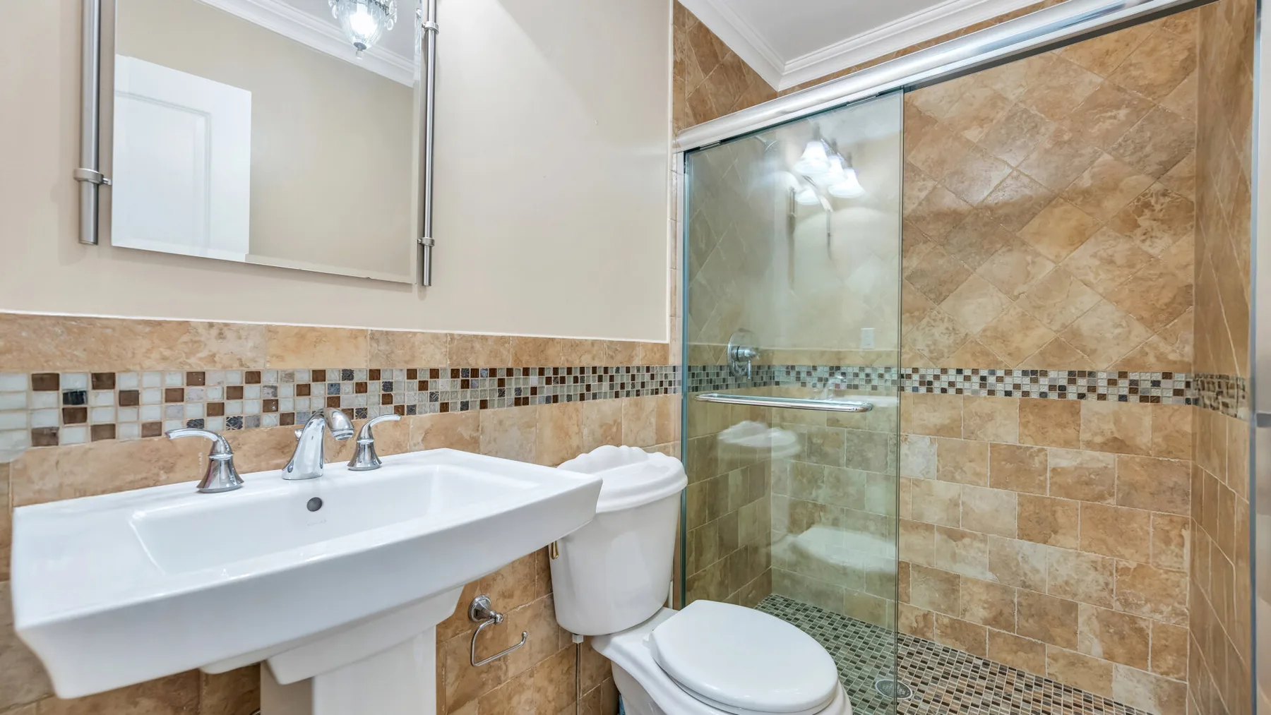 A tiled bathroom with a sink, toilet, and glass shower.