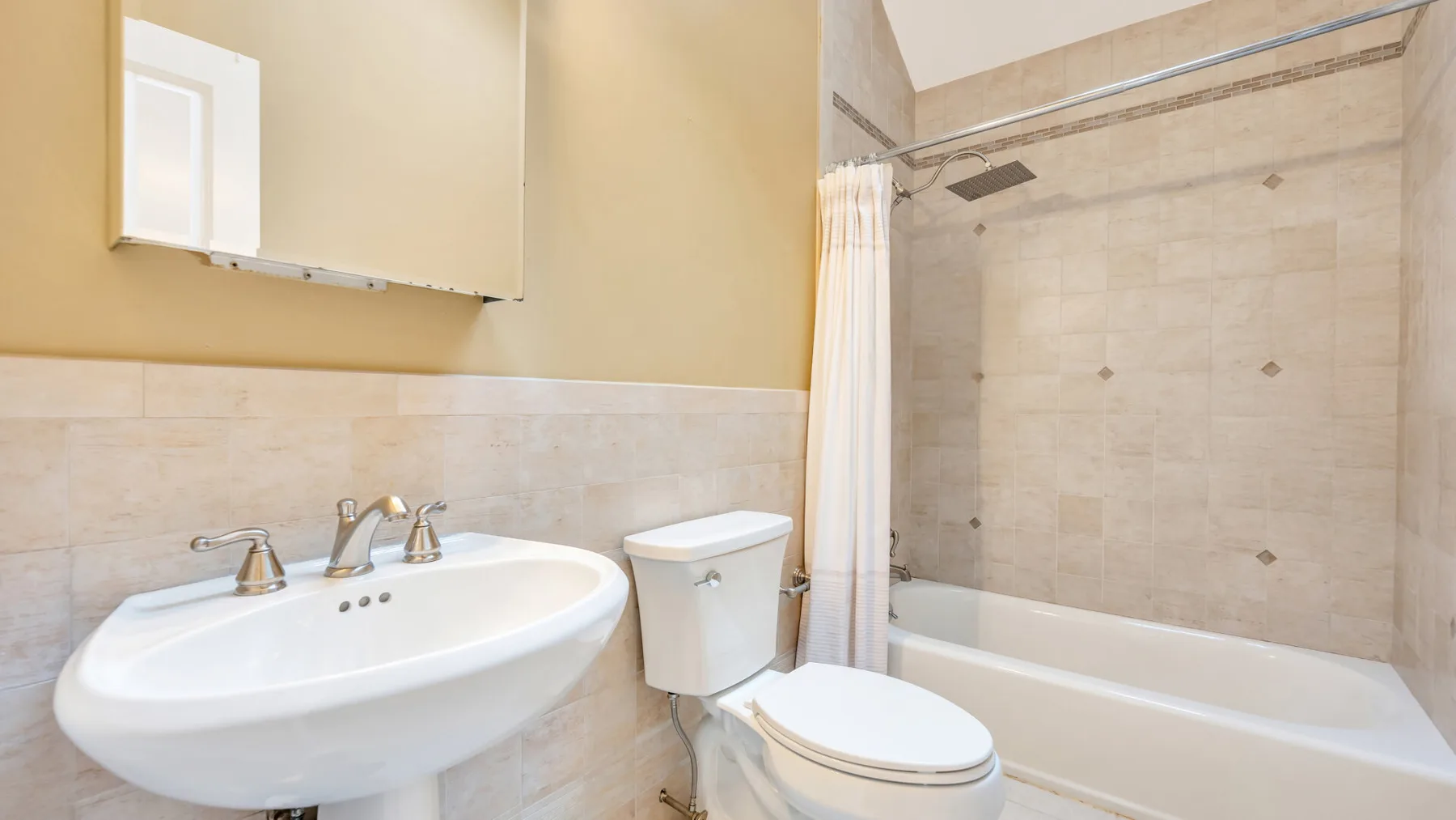 A bathroom with a sink, toilet, and bathtub behind a shower curtain.