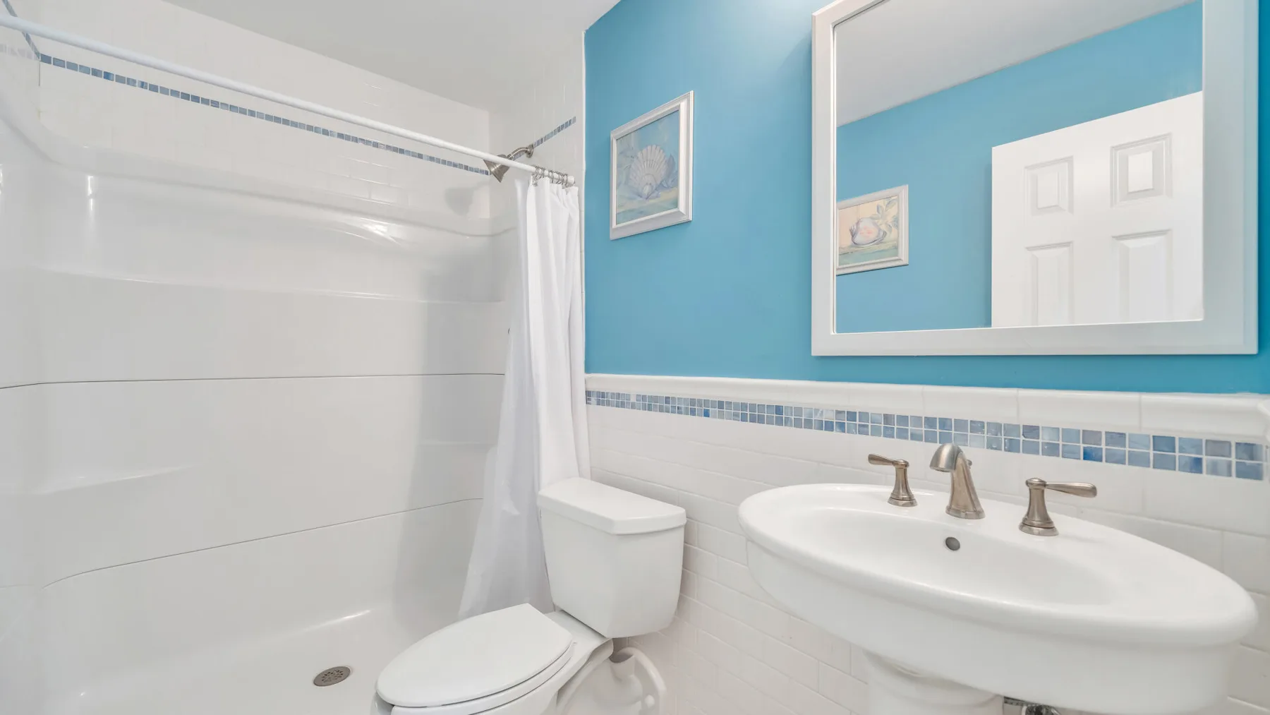 A bright bathroom with a sink, toilet, and shower curtain.