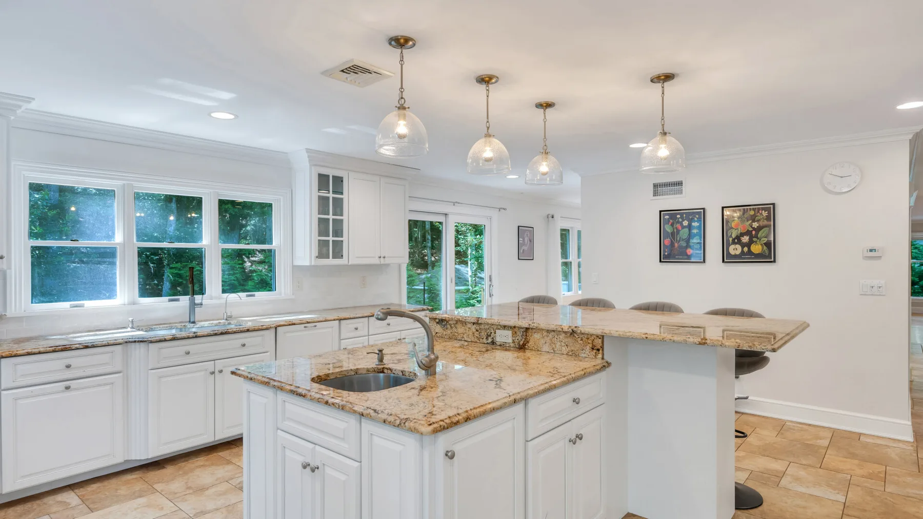 A bright kitchen with white cabinetry, stone countertops, and a central island.