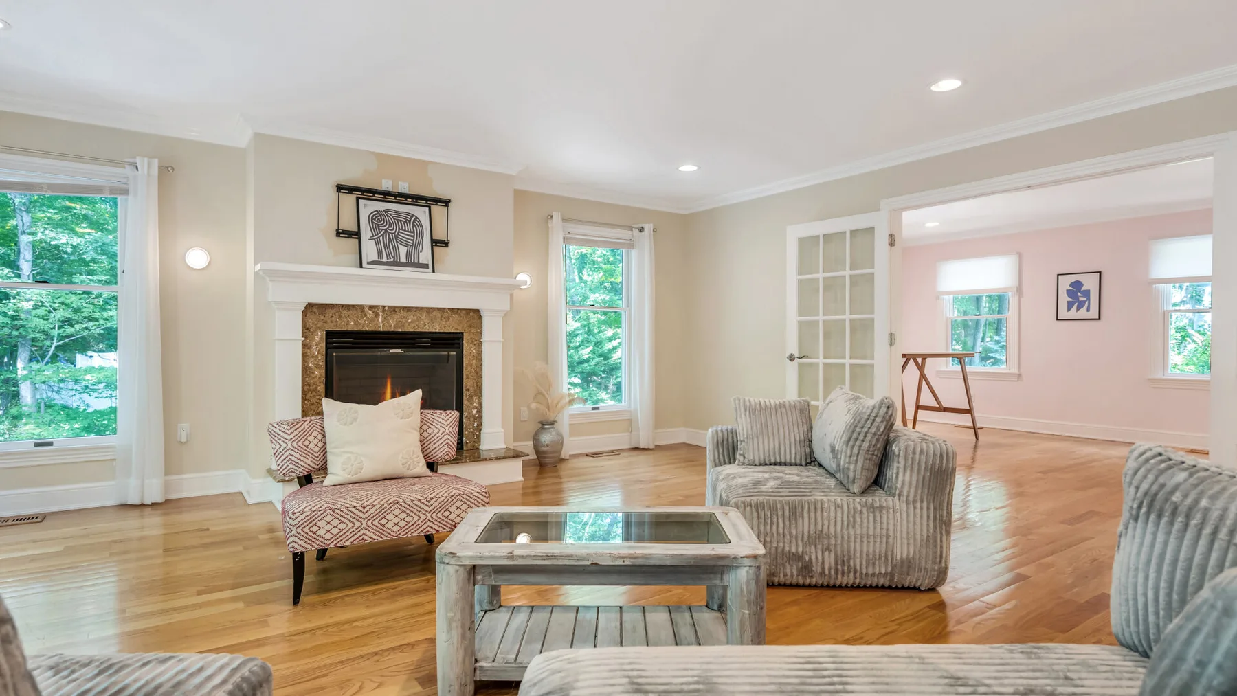 A bright living room with seating, a glass coffee table, and a fireplace.